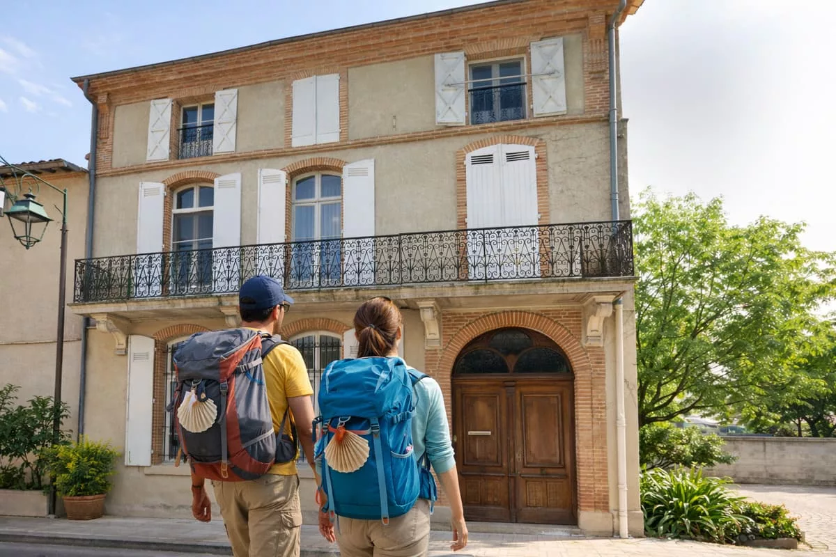 reservation-chambres-hotes-moissac-pelerins-chez-ma-poule Pèlerins arrivant à pied devant la maison d’hôtes Chez Ma Poule à Moissac pour réserver leur étape