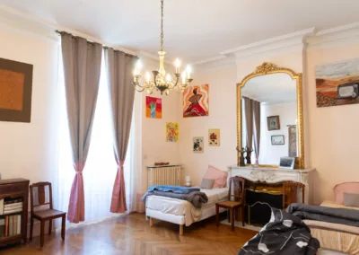 Dortoir spacieux avec plusieurs lits simples et cheminée dans une maison d’hôtes à Moissac